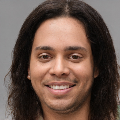 Joyful white young-adult male with long  brown hair and brown eyes
