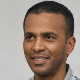 Joyful latino young-adult male with short  black hair and brown eyes