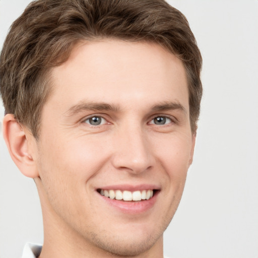 Joyful white young-adult male with short  brown hair and grey eyes