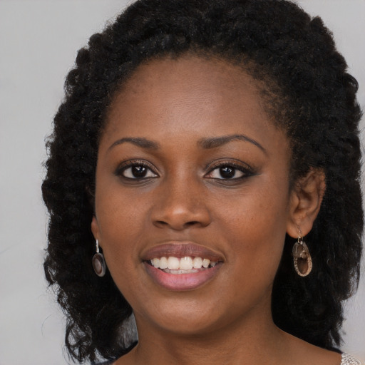 Joyful black young-adult female with long  brown hair and brown eyes