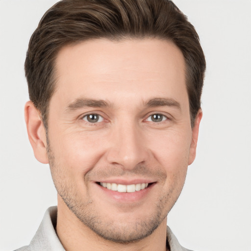 Joyful white young-adult male with short  brown hair and grey eyes