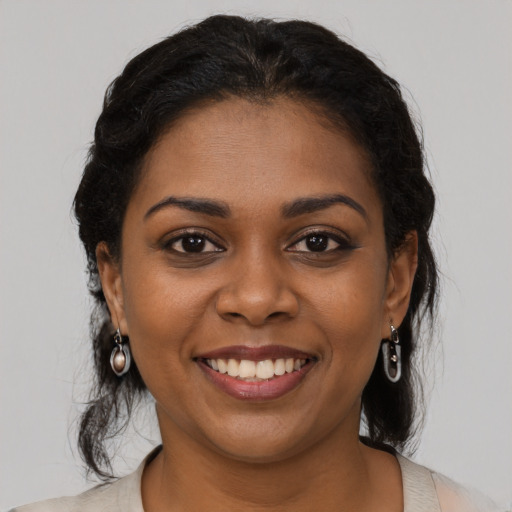 Joyful black young-adult female with long  black hair and brown eyes