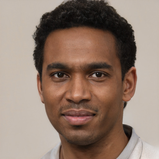 Joyful black young-adult male with short  black hair and brown eyes