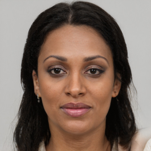 Joyful black young-adult female with long  brown hair and brown eyes
