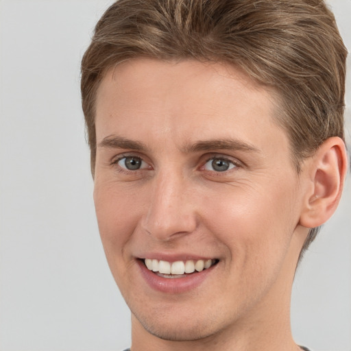 Joyful white young-adult male with short  brown hair and grey eyes