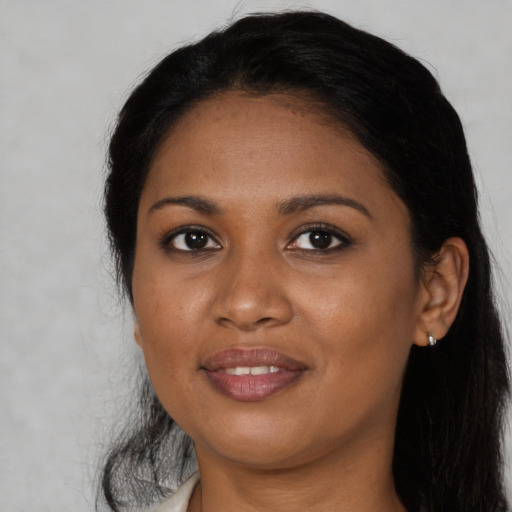 Joyful black young-adult female with long  brown hair and brown eyes