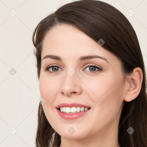 Joyful white young-adult female with long  brown hair and grey eyes