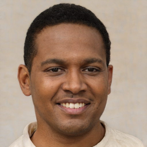 Joyful black young-adult male with short  brown hair and brown eyes