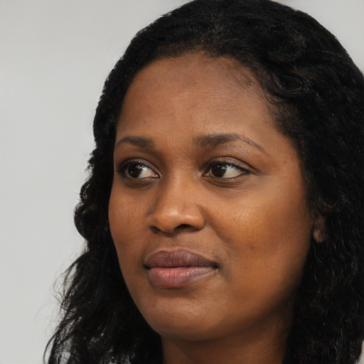 Joyful black young-adult female with long  black hair and brown eyes