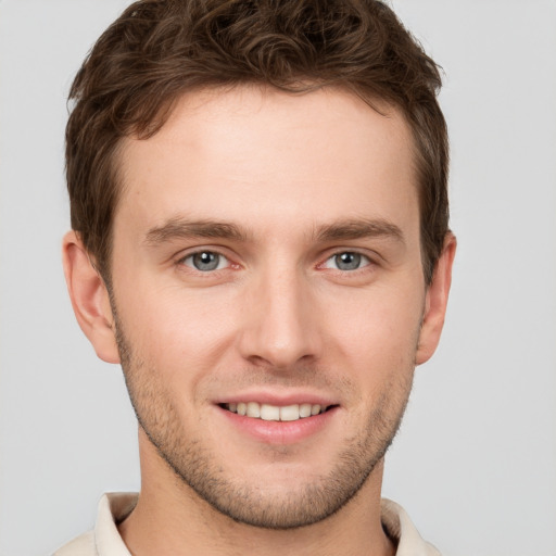 Joyful white young-adult male with short  brown hair and grey eyes