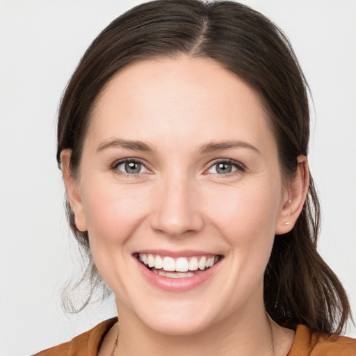 Joyful white young-adult female with medium  brown hair and grey eyes