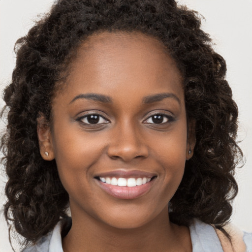 Joyful black young-adult female with long  brown hair and brown eyes