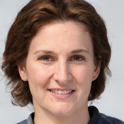 Joyful white adult female with medium  brown hair and grey eyes