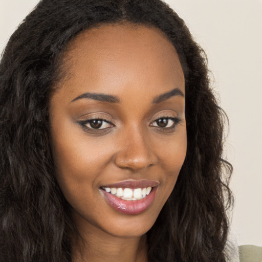 Joyful black young-adult female with long  brown hair and brown eyes