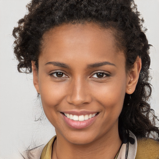 Joyful black young-adult female with long  brown hair and brown eyes