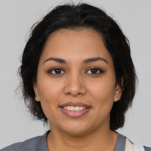 Joyful latino young-adult female with medium  brown hair and brown eyes