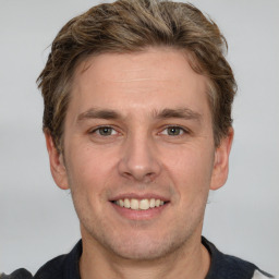 Joyful white young-adult male with short  brown hair and grey eyes