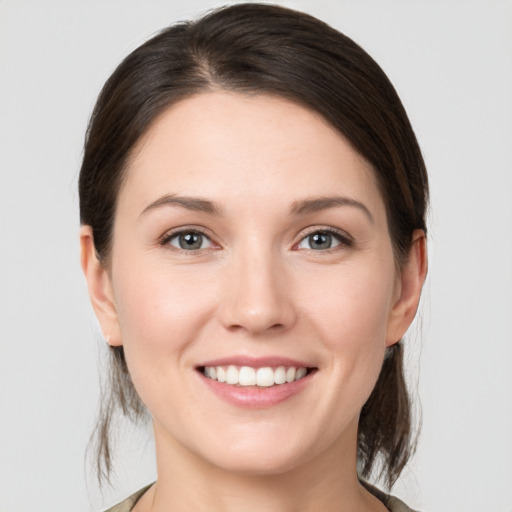 Joyful white young-adult female with medium  brown hair and grey eyes