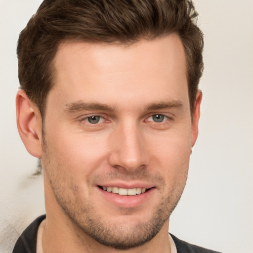 Joyful white young-adult male with short  brown hair and grey eyes