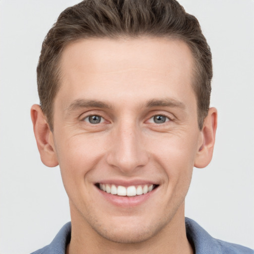 Joyful white young-adult male with short  brown hair and grey eyes