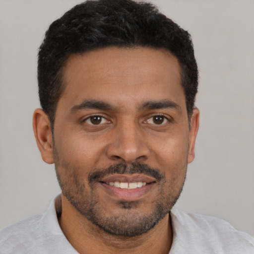 Joyful latino young-adult male with short  black hair and brown eyes