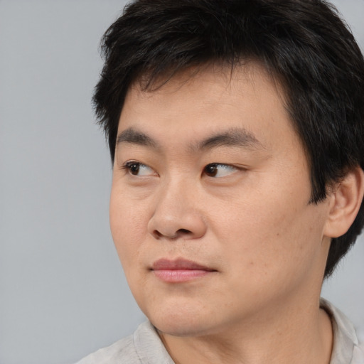 Joyful asian young-adult male with short  brown hair and brown eyes