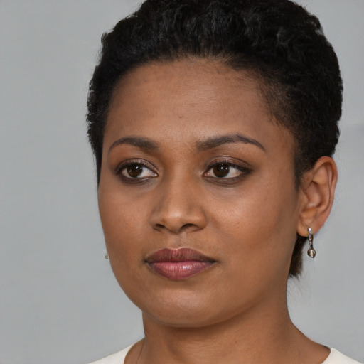 Joyful black young-adult female with short  black hair and brown eyes