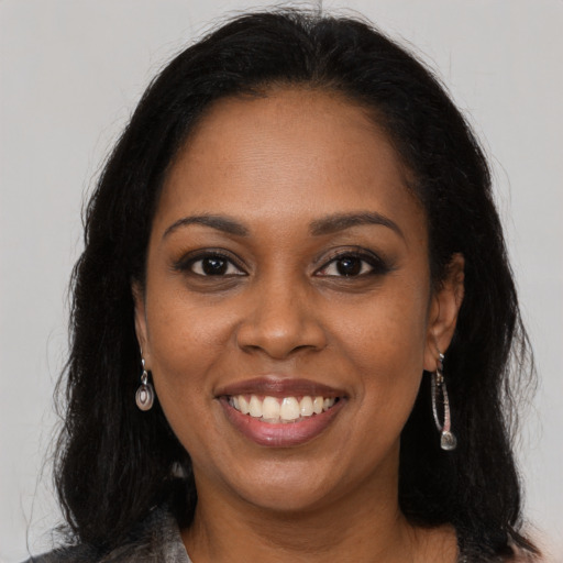 Joyful black young-adult female with long  brown hair and brown eyes