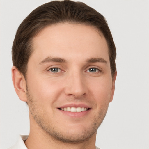 Joyful white young-adult male with short  brown hair and grey eyes