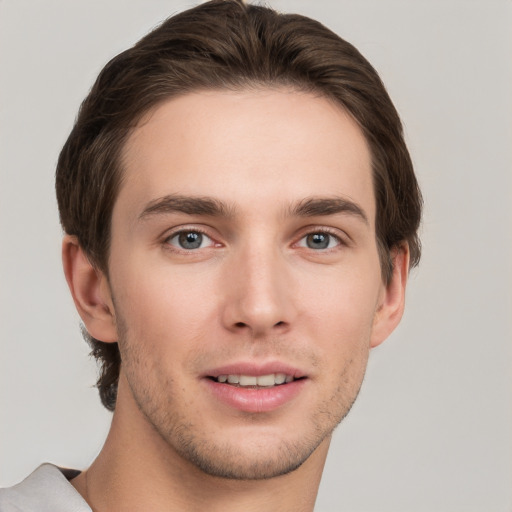 Joyful white young-adult male with short  brown hair and grey eyes