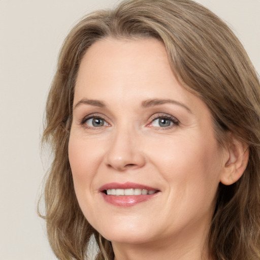 Joyful white adult female with long  brown hair and grey eyes