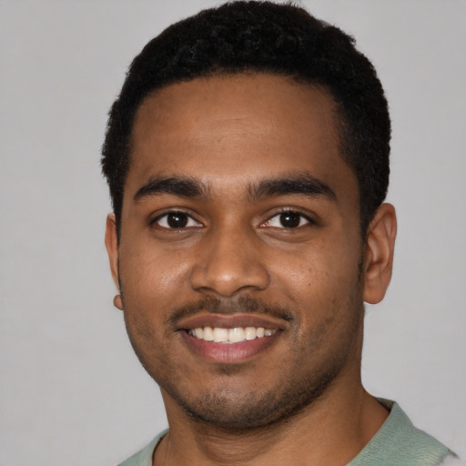 Joyful black young-adult male with short  black hair and brown eyes