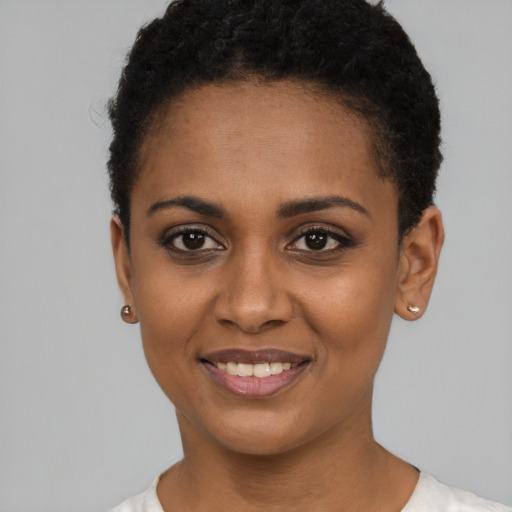 Joyful black young-adult female with short  black hair and brown eyes