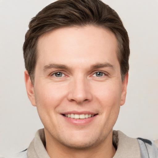 Joyful white young-adult male with short  brown hair and grey eyes