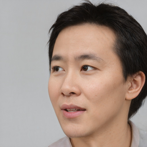 Joyful asian young-adult male with short  brown hair and brown eyes