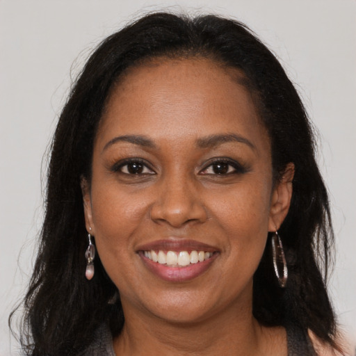 Joyful black young-adult female with long  brown hair and brown eyes