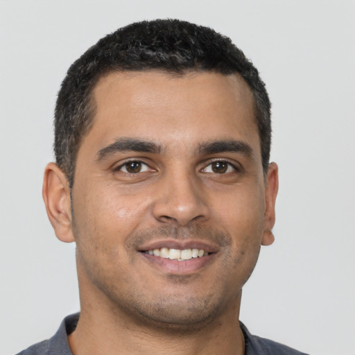 Joyful latino young-adult male with short  black hair and brown eyes