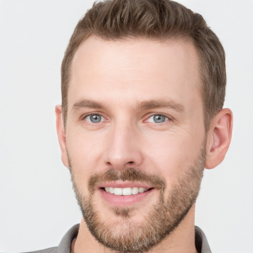 Joyful white young-adult male with short  brown hair and grey eyes