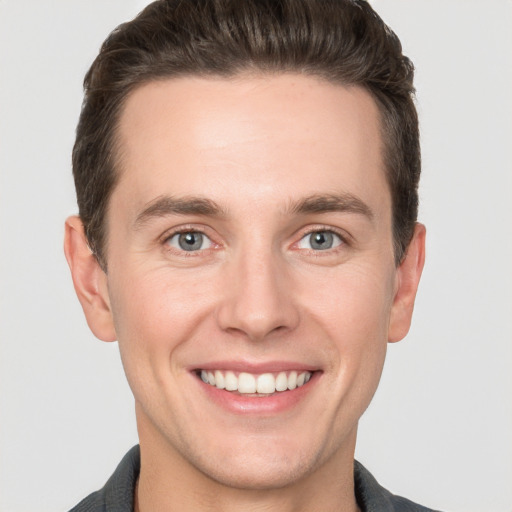 Joyful white young-adult male with short  brown hair and grey eyes