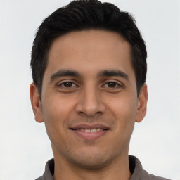 Joyful latino young-adult male with short  brown hair and brown eyes