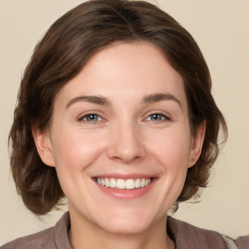 Joyful white young-adult female with medium  brown hair and grey eyes