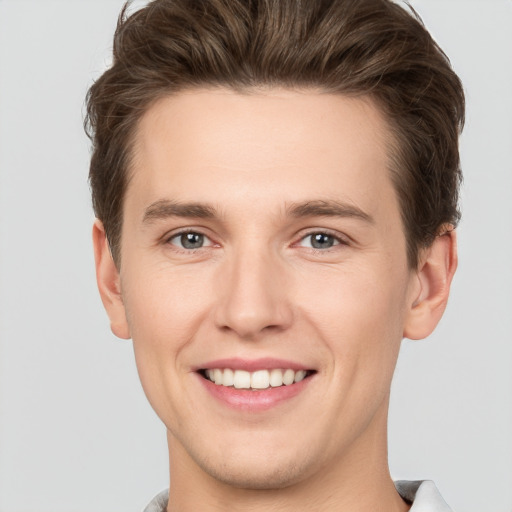 Joyful white young-adult male with short  brown hair and grey eyes