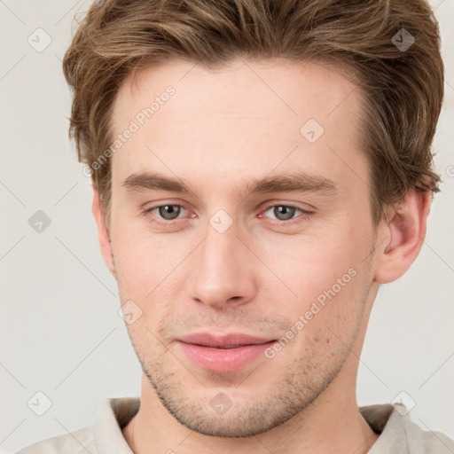 Joyful white young-adult male with short  brown hair and grey eyes