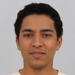 Joyful latino young-adult male with short  black hair and brown eyes