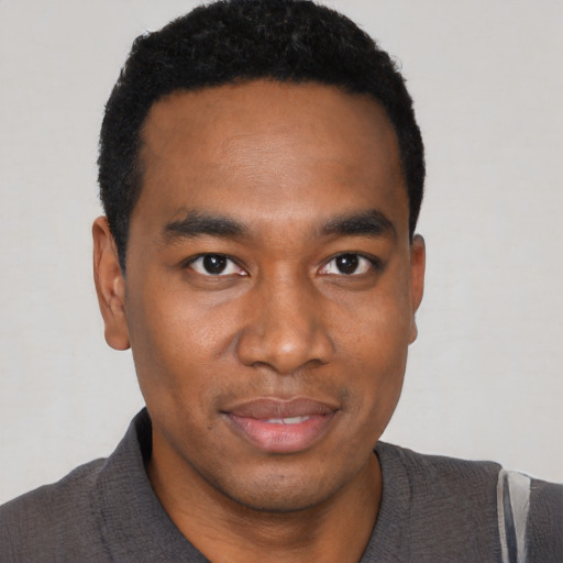 Joyful black young-adult male with short  black hair and brown eyes