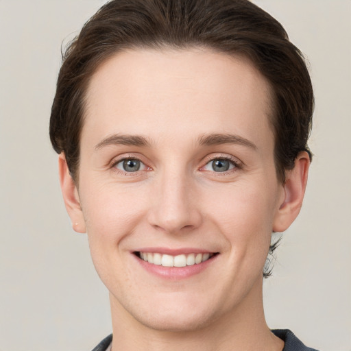 Joyful white young-adult female with short  brown hair and grey eyes