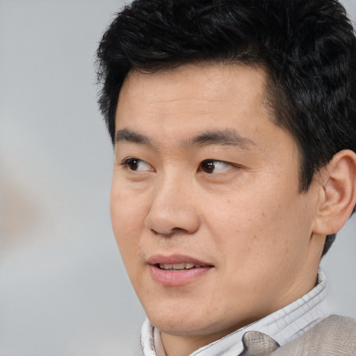 Joyful asian young-adult male with short  black hair and brown eyes