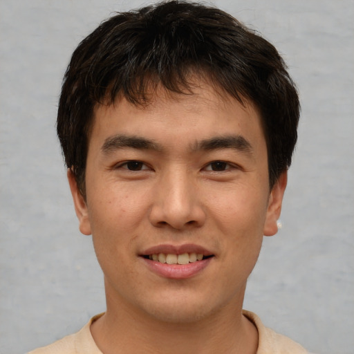 Joyful asian young-adult male with short  brown hair and brown eyes