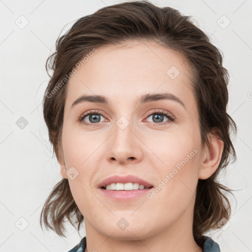 Joyful white young-adult female with medium  brown hair and grey eyes