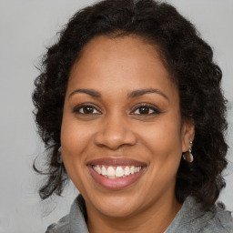 Joyful black adult female with long  brown hair and brown eyes